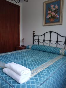 een slaapkamer met een blauw bed en handdoeken bij Puente Villanueva dreans in Medina de Pomar