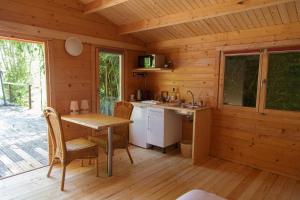 eine Küche in einer Holzhütte mit einem Tisch und Stühlen in der Unterkunft CABANE BAMBOU in Fronsac