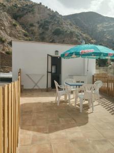 un patio con mesa, sillas y sombrilla en Casa Boneta Alpujarra Almeria-Alboloduy, en Almería
