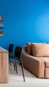 um sofá e cadeiras num quarto com uma parede azul em Apartamento Ondas Praia Resort em Porto Seguro