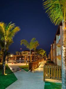 Apartamento Ondas Praia Resort في بورتو سيغورو: صف من أشجار النخيل بجانب مبنى في الليل