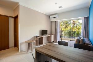 a living room with a dining room table and a television at Apartamento Ondas Praia Resort in Porto Seguro