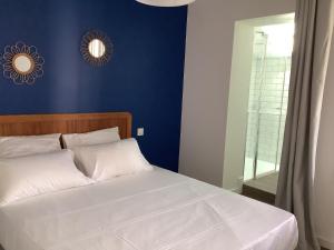 - une chambre avec un lit blanc et un mur bleu dans l'établissement Trinquet Bordatxo, à Saint-Jean-de-Luz