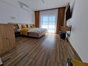 um quarto com uma cama e piso em madeira em Pensiunea Harmony Băile Felix em Baile Felix