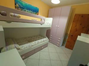 una piccola camera con letto a castello e armadio di Villetta "Poesia" a 50 m dal mare con giardino e parking a Torre dell'Orso