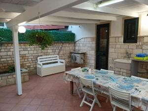 eine Terrasse mit einem Tisch, Stühlen und einem Herd in der Unterkunft Villetta Poesia 50 m dal mare con giardino e parcheggio in Torre dell'Orso