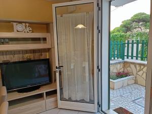 eine Glasschiebetür, die auf eine Terrasse mit einem TV führt in der Unterkunft Villetta Poesia 50 m dal mare con giardino e parcheggio in Torre dell'Orso