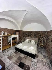 sypialnia z łóżkiem i kamienną ścianą w obiekcie La Piccola Grotta Ursino w Katanii
