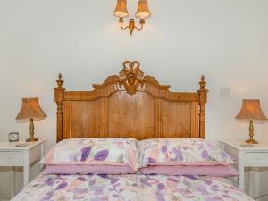 a bed with a wooden headboard and two night stands at Sunbeck Gatehouse in Thormanby