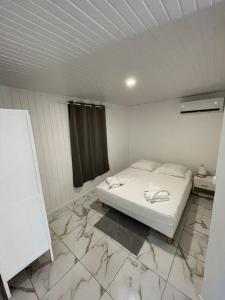 a white bed in a room with marble floors at Location AKAZAW in Pointe-Noire