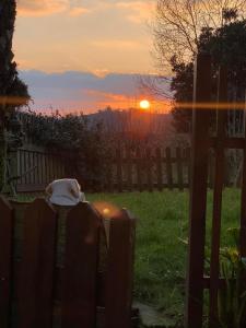 una puesta de sol en un patio con una valla y el sol en Posada El Pareón en Sirviella