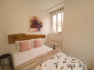 um quarto com uma cama com almofadas cor-de-rosa e uma janela em Casinha da Patricia na Nazaré
