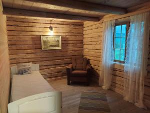 a bedroom with a bed and a chair and a window at Villmarksgård tømmerstue in Hattfjelldal
