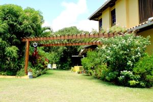 a wooden pergola in the middle of a garden at Madalena Apart in Praia do Forte