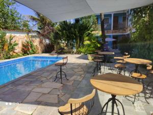 un patio con mesas y sillas junto a una piscina en POUSADA CARVALHO, en Pirenópolis