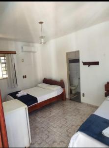 a bedroom with two beds and a bathroom with a toilet at POUSADA CARVALHO in Pirenópolis