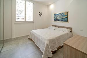 a white bedroom with a bed and a window at AL BAYDA in Palermo