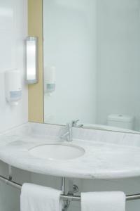 lavabo blanco con espejo y toallas en Ibis Hermosillo, en Hermosillo