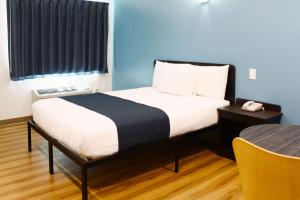 Motel 6 Rexburg, ID في ريكسبورغ: غرفة صغيرة بها سرير وطاولة