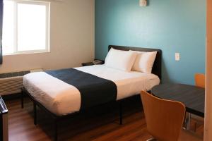 a bedroom with a bed with a table and a window at Motel 6 Rexburg, ID in Rexburg