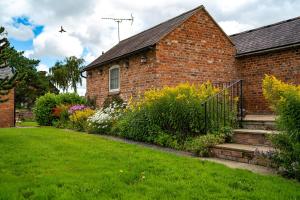 a brick house with a green yard with flowers at Higher Farm in Malpas