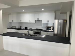 cocina con armarios blancos y nevera de acero inoxidable en Beachside & Jetty View Apartment 1 - Admirals Apartment, en Streaky Bay