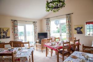 a dining room with tables and chairs and windows at Higher Farm in Malpas