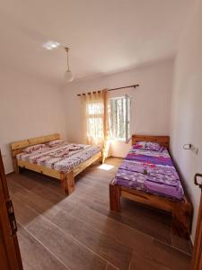 a bedroom with two beds and a window at Bujtinat Skenderi Gjinar in Gjinar