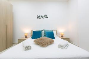 1 cama blanca grande con almohadas y mantas azules en Brand new apartment in Sliema 2 min by the sea, en Sliema