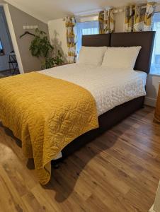 a bedroom with a large bed with a yellow bedspread at Gull Wing Guesthouse in Lowestoft