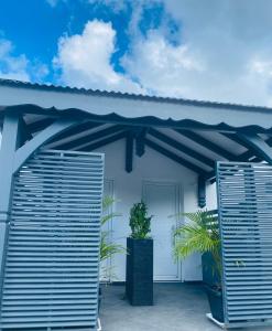 a white house with a blue roof and two shutters at K'Noly in Baie-Mahault