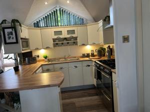 a kitchen with white cabinets and a stove top oven at Jungle lodge in Lymington