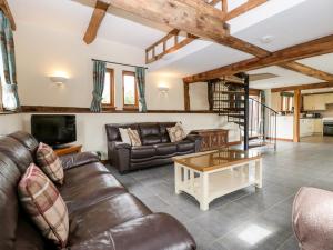 a living room with a leather couch and a coffee table at The Hop Kiln in Pembridge