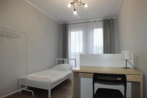 Schlafzimmer mit einem Schreibtisch, einem Bett und einem Fenster in der Unterkunft Apartamenty Nila in Krakau