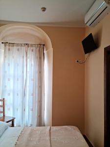 a bedroom with a bed and a window with a television at Hotel Plateros in Córdoba