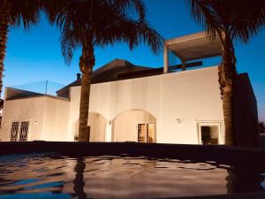 una casa blanca con palmeras delante en Il Melograno chic&nature, en Santa Maria La Carità