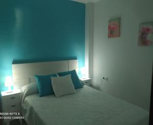 una camera da letto con un letto con pareti blu e due lampade di El Ancla a Chiclana de la Frontera
