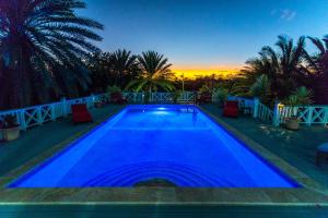 una grande piscina blu con un tramonto sullo sfondo di Villa Lazy Daze a Jolly Harbour