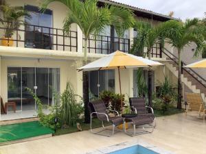 a patio with chairs and an umbrella next to a house at Pousada Villa Encantada LGBTQIAPlus in Salvador