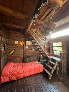 um quarto com uma cama vermelha num chalé de madeira em Cabaña La Triada, Grupo Cabaña La Triada em Río Ceballos