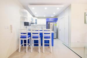una cucina con pareti bianche e sgabelli blu di DOLCE VILLAS AT HARMONY 2 a Santiago de los Caballeros