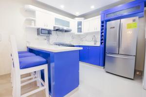 una cucina blu e bianca con frigorifero e sgabello di DOLCE VILLAS AT HARMONY 2 a Santiago de los Caballeros
