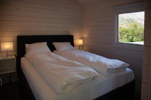 a bedroom with a bed with white sheets and a window at Dalasetur in Hofsós