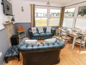 a living room with a leather couch and a table at Driftwood in Haverfordwest