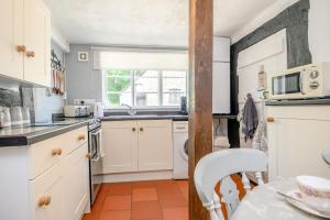 a kitchen with white cabinets and a table and a microwave at Fern Hall Cottage in Upper Welson +18 photos