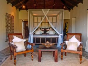 a bedroom with a bed with two chairs and a table at Firefly Estate Bequia in Crescent Beach