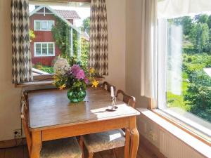 wazon kwiatów na drewnianym stole w oknie w obiekcie 5 person holiday home in FLODA w mieście Floda