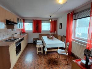 eine Küche mit einem Tisch und roten Vorhängen darin in der Unterkunft Spacious holiday home in Neureichenau Schimmelbach in Neureichenau