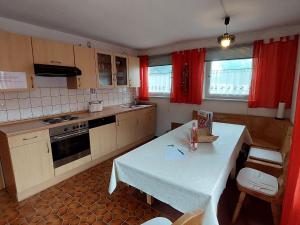 eine Küche mit einem weißen Tisch und roten Vorhängen in der Unterkunft Spacious holiday home in Neureichenau Schimmelbach in Neureichenau