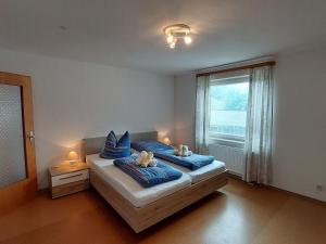 ein Schlafzimmer mit einem Bett mit blauen Kissen und einem Fenster in der Unterkunft Spacious holiday home in Neureichenau Schimmelbach in Neureichenau